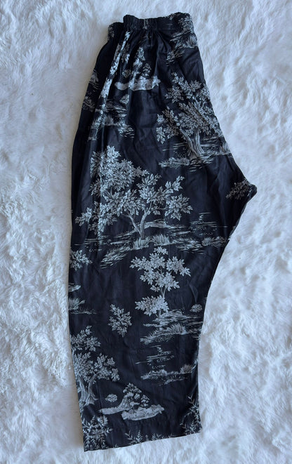 Black pants with white floral pattern on a textured white background