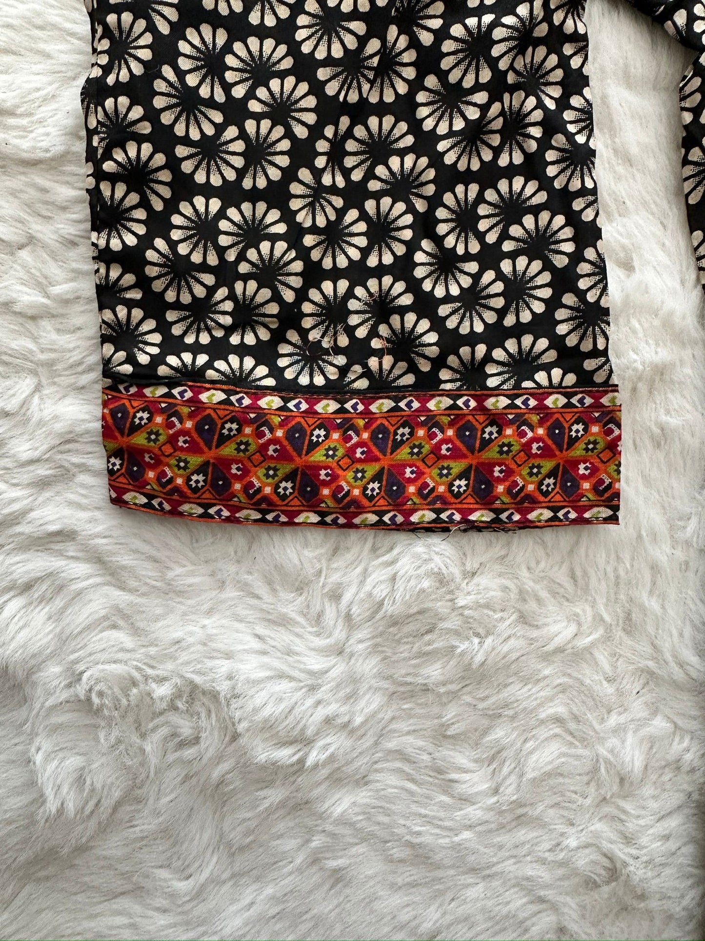Fabric with black floral pattern on top and multicolored border arm