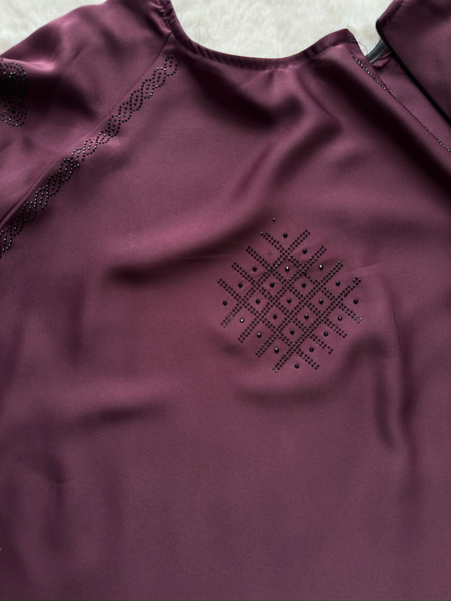 Front view of plum Nida abaya featuring subtle stone work on chest with flowing full flare silhouette