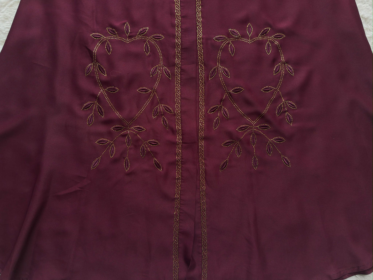 Maroon fabric with embroidered heart design on a neutral background