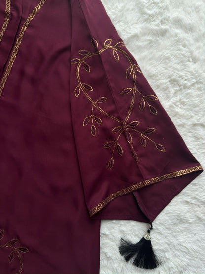 Close-up of maroon premium Nida abaya showing gold stonework sleeves with tassel detailing