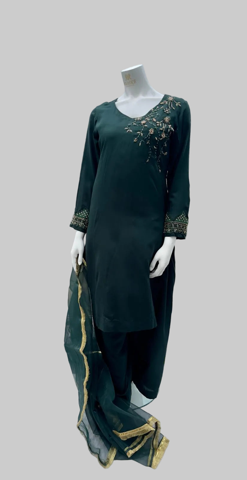 Green embroidered outfit on a mannequin with a cityscape background