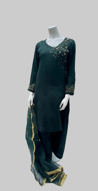Green embroidered outfit on a mannequin with a cityscape background